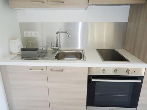 Il comprend une cuisine équipée d'un évier et d'une cuisinière. dans l'établissement Bel appartement 2 pièces climatisé 500m centre, à Cavalaire-sur-Mer