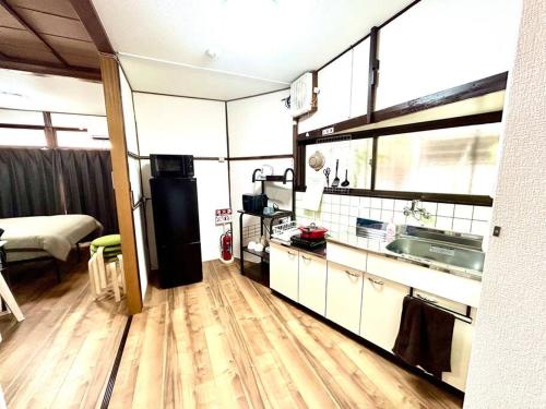 a room with a kitchen with a sink and a bed at ゲストハウスEn 折尾駅前邸 in Orio