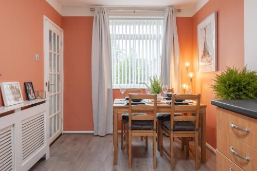 a dining room with orange walls and a wooden table and chairs at Cheshire Retreat, close to Tatton Park in Knutsford