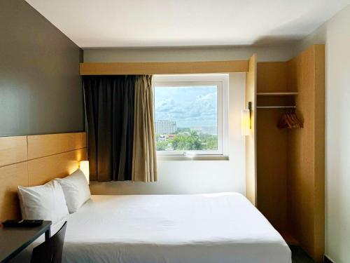 Un dormitorio con una cama blanca y una ventana. en Ibis Merida, en Mérida