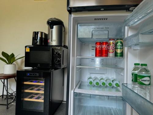 an open refrigerator filled with drinks and soda at Tanouy Garden in Baan Khai