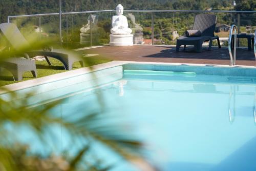 a swimming pool with a statue in the background at Ermal Village in Vieira do Minho