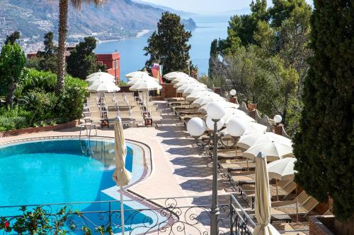 a row of chairs and umbrellas next to a swimming pool at Hotel Ariston and Palazzo Santa Caterina in Taormina