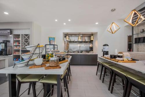 Hilton Garden Inn Oklahoma City Midtown في مدينة اوكلاهوما: مطعم مع طاولات وكراسي ومطبخ