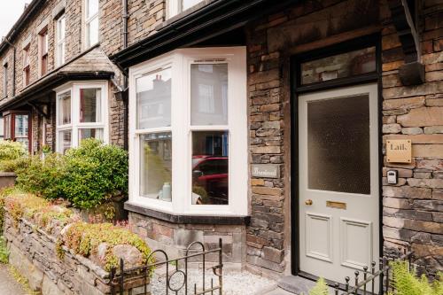 a brick house with a white door and windows at Brantwood - 4 bed home Ambleside in Ambleside