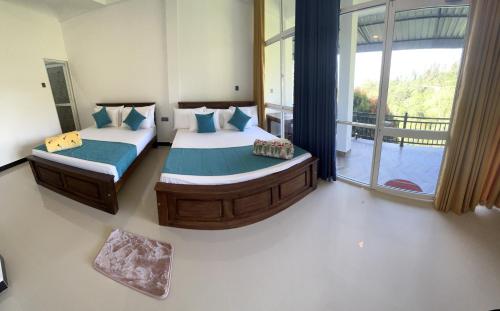 a bedroom with two beds and a large window at Viyanga Homestay in Ella