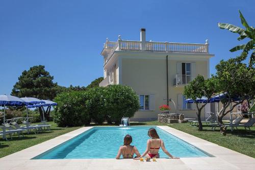 two girls sitting in a swimming pool in front of a house at Primavilla Relais in Gaeta