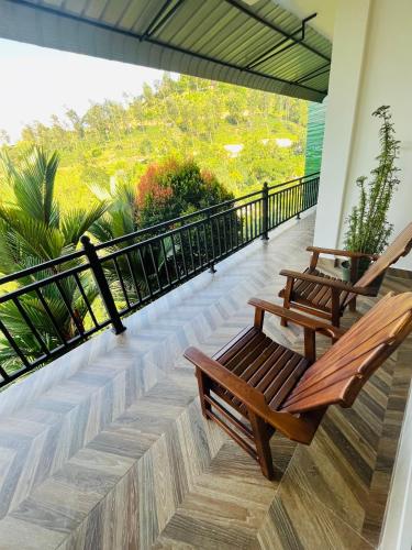 two wooden benches on a balcony with a view at Viyanga Homestay in Ella