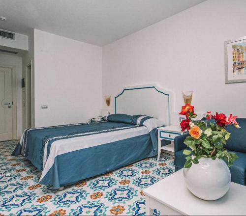 a bedroom with a bed and a vase with flowers at Hotel Ferretti in Diamante