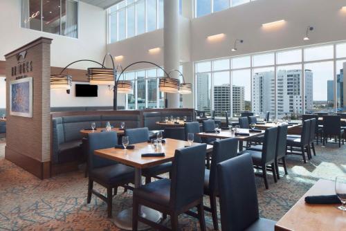 a restaurant with tables and chairs and large windows at Embassy Suites By Hilton Sarasota in Sarasota