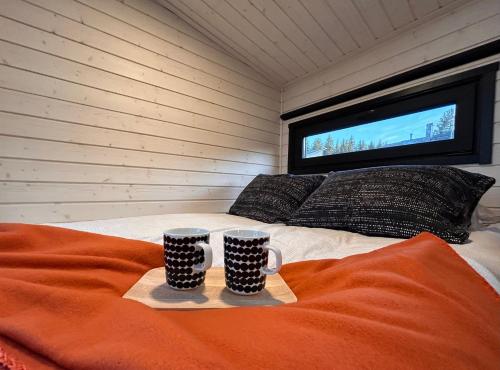 a room with two cups on a bed with a tv at The Saunacabin Enchanted Lapland in Rovaniemi