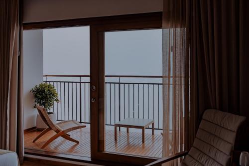 a room with a balcony with a chair and a table at The Valle by Kondody Hotels in Munnar