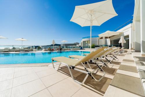 a pool with lounge chairs and an umbrella at Apollo Blue in Faliraki