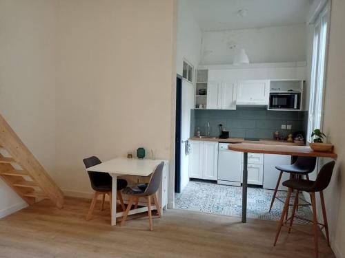 une cuisine avec des armoires blanches et une table et des chaises dans l'établissement Charmant studio avec cour en centre-ville, à Nîmes