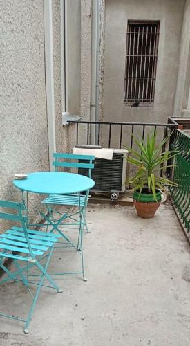 une table bleue et des chaises assises à côté d'un balcon dans l'établissement Charmant studio avec cour en centre-ville, à Nîmes