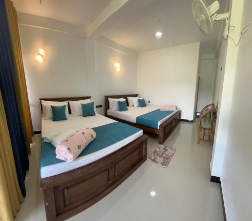 a bedroom with two beds with blue pillows at Viyanga Homestay in Ella