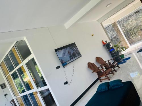 a living room with a tv on a white wall at Viyanga Homestay in Ella