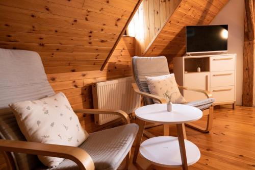 a living room with chairs and a table and a tv at Penzion Statek u Rajtrů in Bedřichov