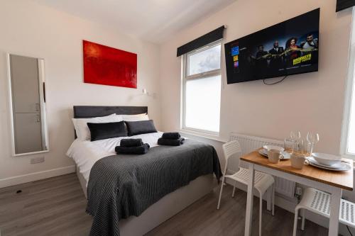 a bedroom with a bed and a table and a tv at Boutique Studios by Luxestays Fulham Broadway in London
