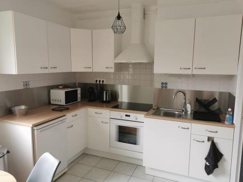 une cuisine avec des armoires blanches, un évier et un micro-ondes dans l'établissement Studio Coatserho, à Lorient