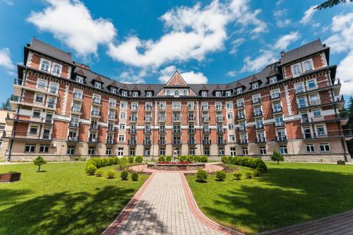 a large brick building with a garden in front at Rewita Kościelisko-Zakopane in Kościelisko
