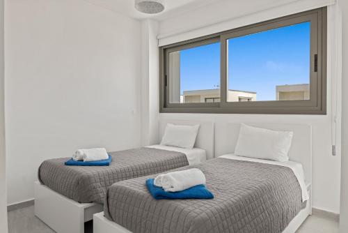 Dos camas en una habitación con ventana. en Serenity Waves Villa 16, en Lárnaca