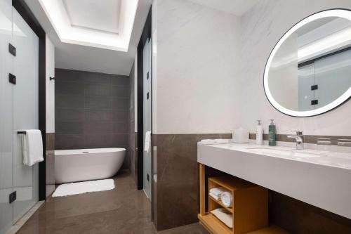 a bathroom with a tub and a sink and a mirror at Hilton Garden Inn Beijing Huaxiang Tiantan Hospital in Beijing