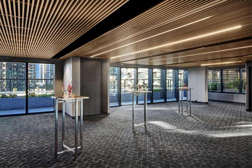 a lobby with two tables in a building with windows at Vibe Hotel Melbourne Docklands in Melbourne