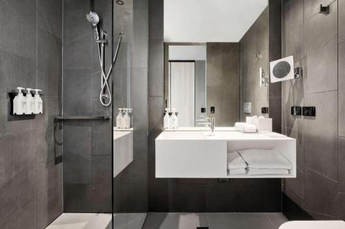 a bathroom with a white sink and a shower at Vibe Hotel Melbourne Docklands in Melbourne