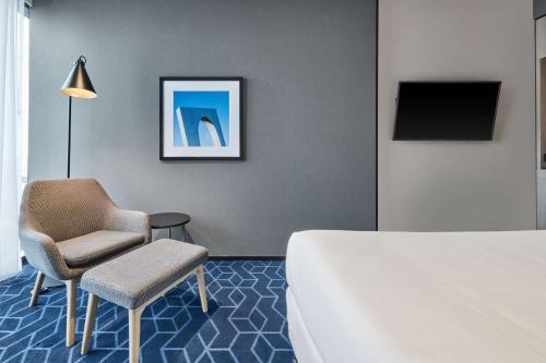 a bedroom with a bed and a chair and a tv at Vibe Hotel Melbourne Docklands in Melbourne