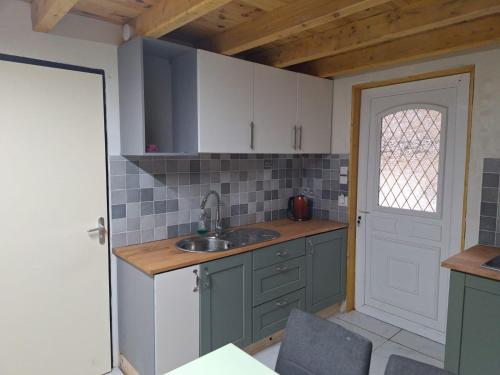 a kitchen with white cabinets and a sink and a door at gite tipi in Faux-la-Montagne