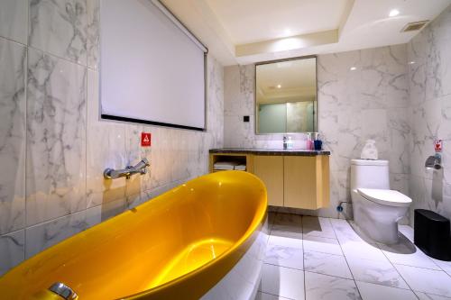 a bathroom with a yellow tub and a toilet at Olah Poshtel Taichung Wenxin in Taichung