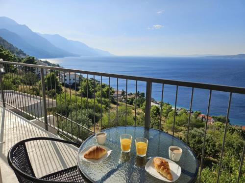 a glass table with two glasses of orange juice on a balcony at New 2 Bedroom, 2 Bathroom Apartment in Pisak in Pisak