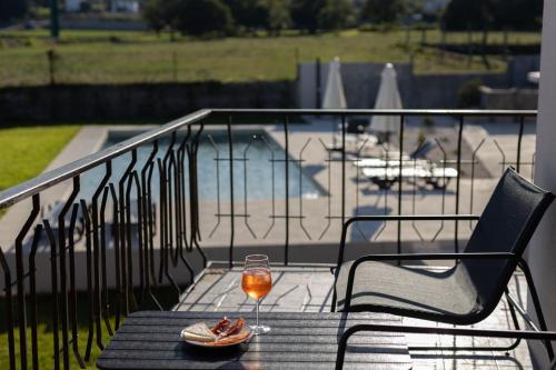 a glass of wine sitting on a table on a balcony at Correia Villa in Barcelos