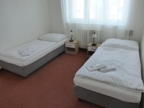 two beds in a room with two tables and a window at Hotel Svornost in Prague
