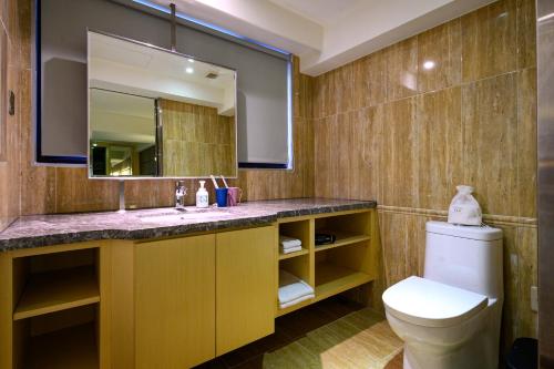 a bathroom with a toilet and a sink and a mirror at Olah Poshtel Taichung Wenxin in Taichung