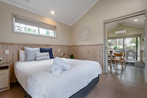 a bedroom with a large white bed and a dining room at BIG4 Tasman Holiday Parks - Ballina in Lennox Head