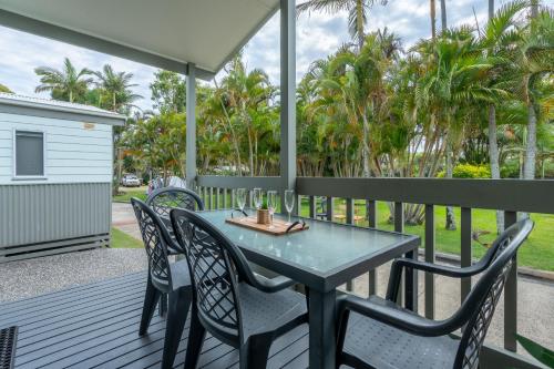 a table and chairs on a deck with palm trees at BIG4 Tasman Holiday Parks - Ballina in Lennox Head