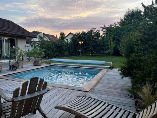une piscine avec une terrasse en bois et deux chaises longues dans l'établissement La remise, à Beaune