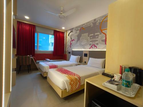 two beds in a hotel room with red curtains at Ginger Pondicherry in Puducherry