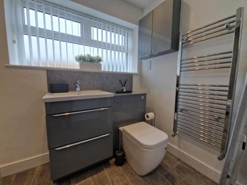 a bathroom with a toilet and a sink and a window at Homely 3 Bedroom home near town centre & only 1 mile from Bike Park Wales in Merthyr Tydfil