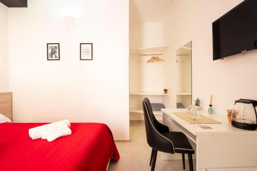 a bedroom with a bed and a desk with a red blanket at Affittacamere Casa Concia in Tortolì