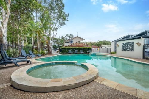 a swimming pool with chairs in front of a house at BIG4 Tasman Holiday Parks - Ballina in Lennox Head