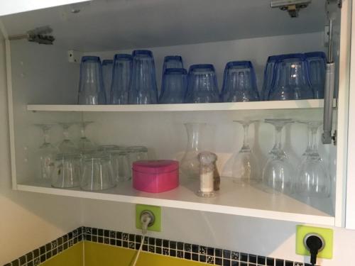 a bunch of glass vases on shelves in a kitchen at Le Sérènity in Le Landin