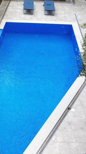 a large blue swimming pool with two blue chairs at Apartmani Milos - Meljine in Herceg-Novi