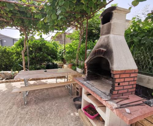 a pizza oven and a picnic table in a backyard at Apartment Adriana in Seget Vranjica