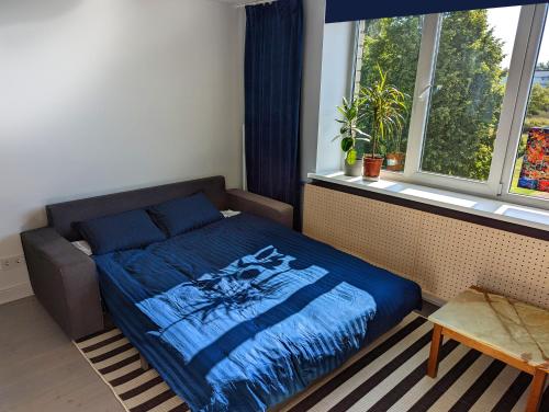 a bedroom with a bed with a blue comforter and a window at Lost & Found 3 - with 4 bikes in Pāvilosta