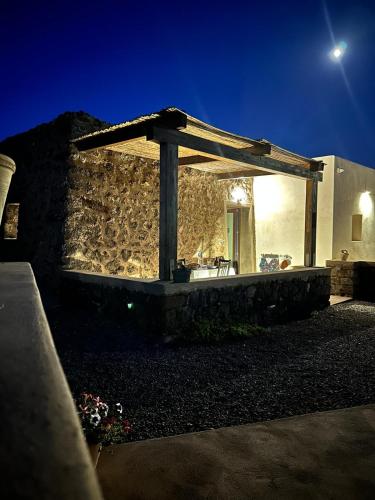 a stone wall with a wooden pergola on it at La Grotta di benikula' in Pantelleria