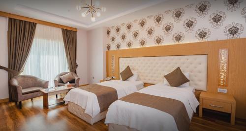 a hotel room with two beds and a chair at Classy Hotel Erbil in Erbil