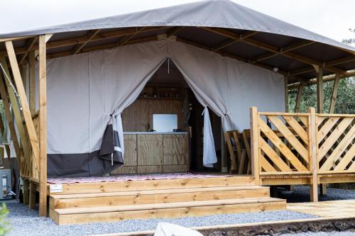a large canvas tent with a wooden porch at Koru - Etna Glamping Experience in Ragalna